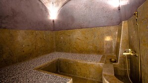 Ein Wellnessraum mit einer rechteckigen Badewanne, einer Duschkabine und einem Marmorboden.