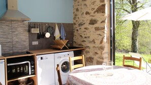 A compact kitchen with a washing machine, microwave, and wooden cabinets. - Renovated farmhouse in the heart of nature in the PNR de Millevaches en Limousin (Sussac)