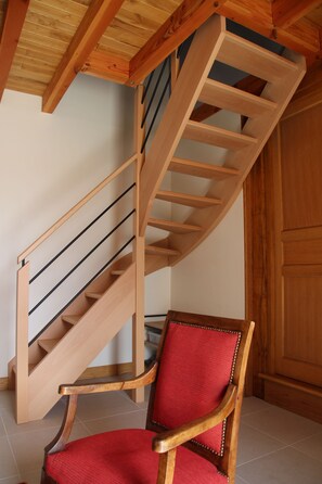 A wooden staircase with a red cushioned chair at the bottom. - Renovated farmhouse in the heart of nature in the PNR de Millevaches en Limousin (Sussac)