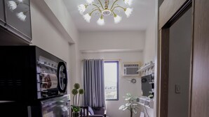 A narrow kitchen with a dining table, chairs, a refrigerator, and a ceiling light fixture. - Beautiful 2-bedroom condo with AC in soothing Muntinlupa (Muntinlupa)