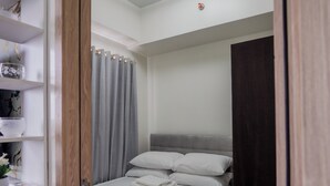 A bedroom with a bed, a wardrobe, a shelf with decorative items, and a ceiling light fixture. - Beautiful 2-bedroom condo with AC in soothing Muntinlupa (Muntinlupa)