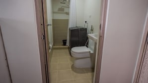 A narrow bathroom with a toilet, sink, and shower area. - Beautiful 2-bedroom condo with AC in soothing Muntinlupa (Muntinlupa)