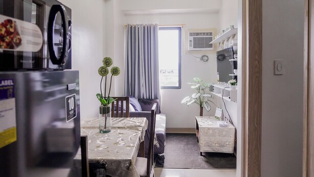 A modern kitchen with a refrigerator, dining table, chairs, and a chandelier. - Beautiful 2-bedroom condo with AC in soothing Muntinlupa (Muntinlupa)