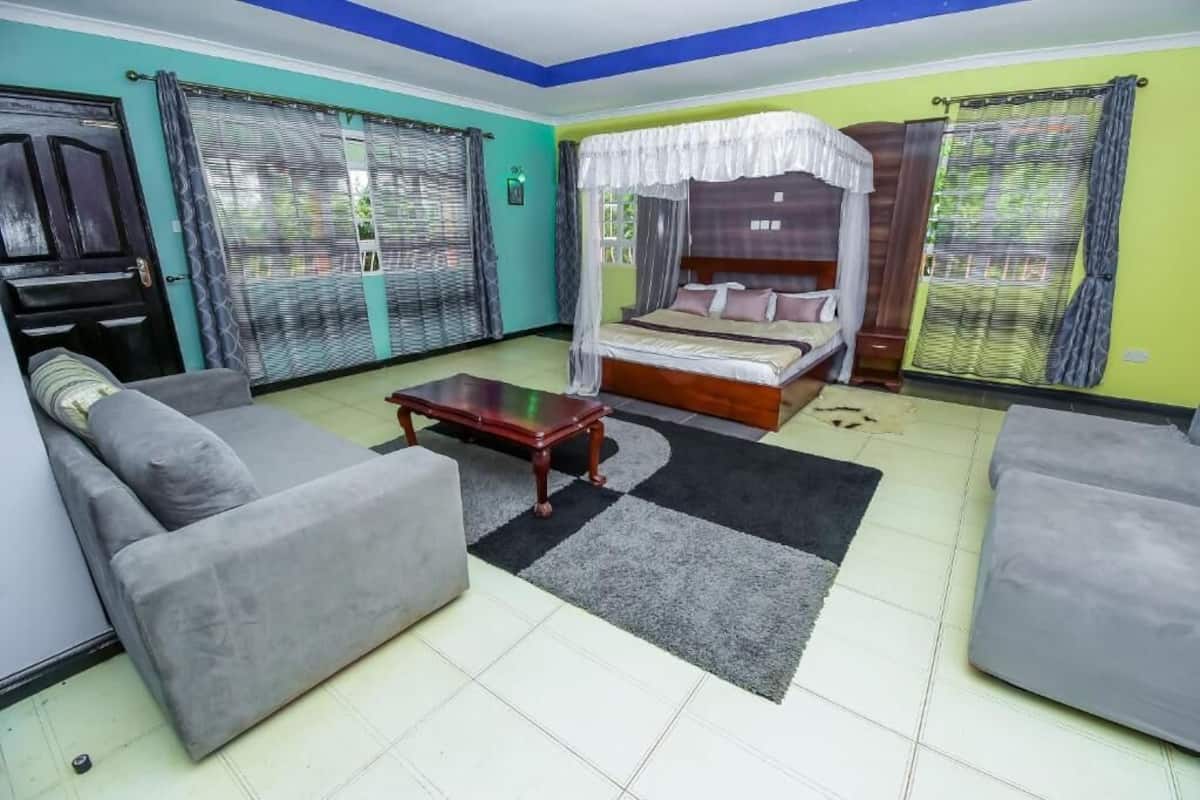 Una habitación con una cama, dos sofás, una mesa de centro y un televisor.