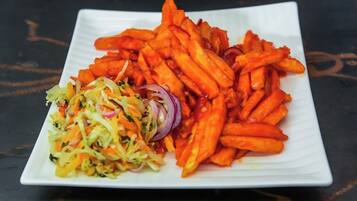 A white rectangular plate with a serving of sweet potato fries and a side salad.