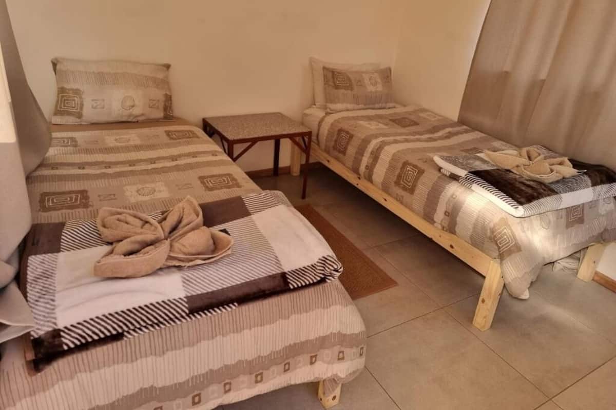 Ein kleines, gemütliches Zimmer mit zwei Einzelbetten, einem Tisch und einer Bank.