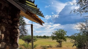 Un bâtiment en pierre avec une allée de gravier menant à un champ d’herbe.