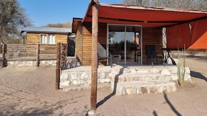 Une cabane rustique avec des fondations en pierre, un revêtement extérieur en bois et un patio couvert.