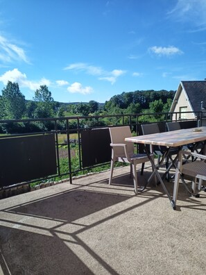 An outdoor patio with a table and chairs, a view of a house, and a fenced garden area. - LE GITE DES DEUX LACS MORVAN NEAR LAC DES SETTONS 9PERS (Planchez)