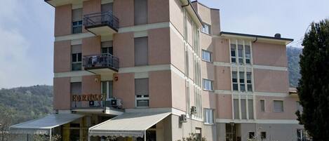 A multi-story hotel with a flat roof, balconies, and a covered entrance area.