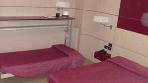 A hotel room with two single beds, a desk with a computer, a telephone, and a small red storage box. - Hotel Fornaci  (Trescore Balneario)