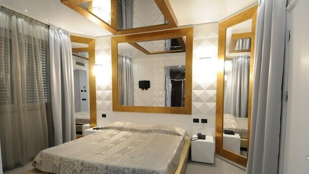 A modern bedroom with a large bed, a bedside table, a mirror, and a wardrobe. - Hotel Fornaci  (Trescore Balneario)