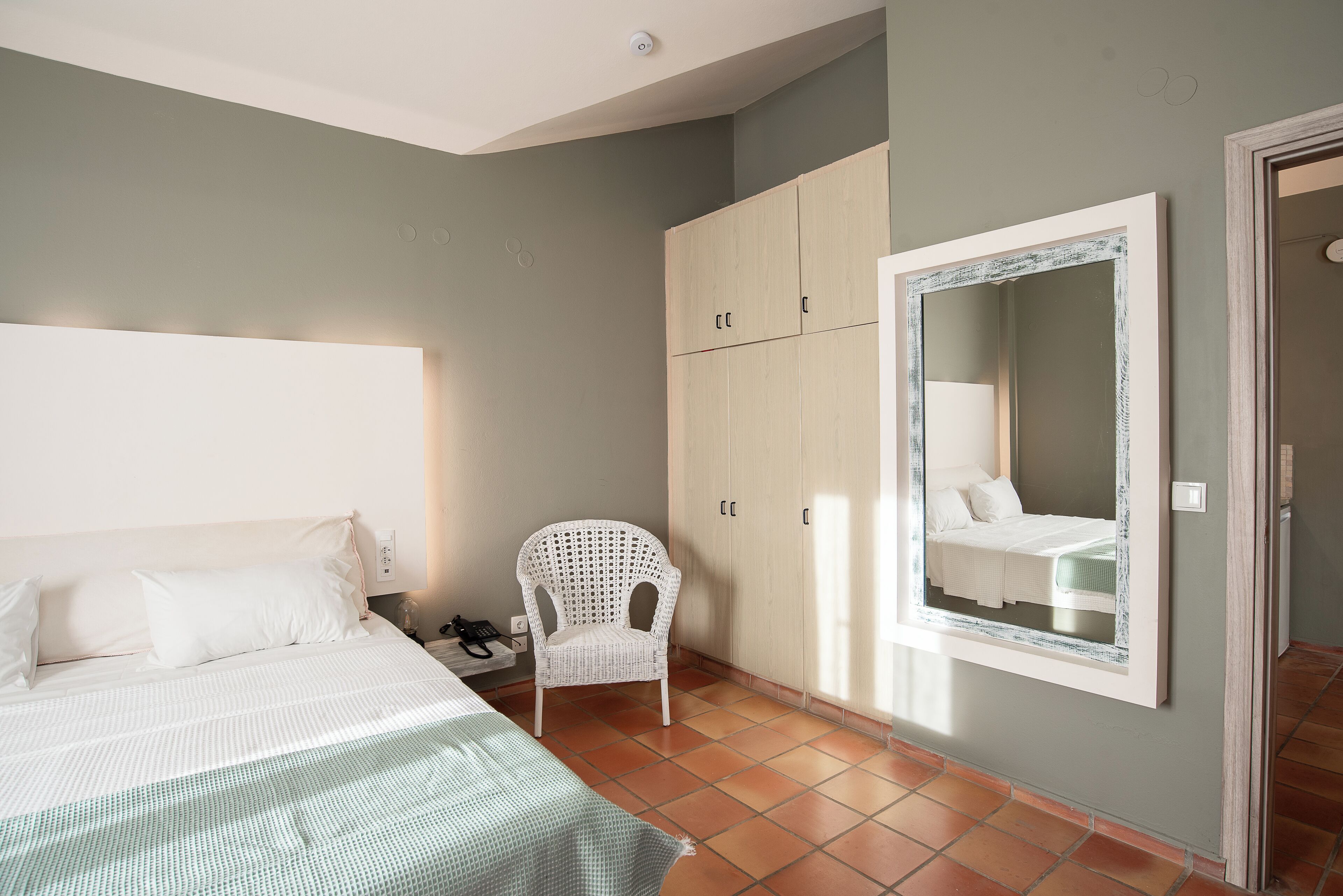 Una camera da letto con un letto, una sedia, un armadio e uno specchio.