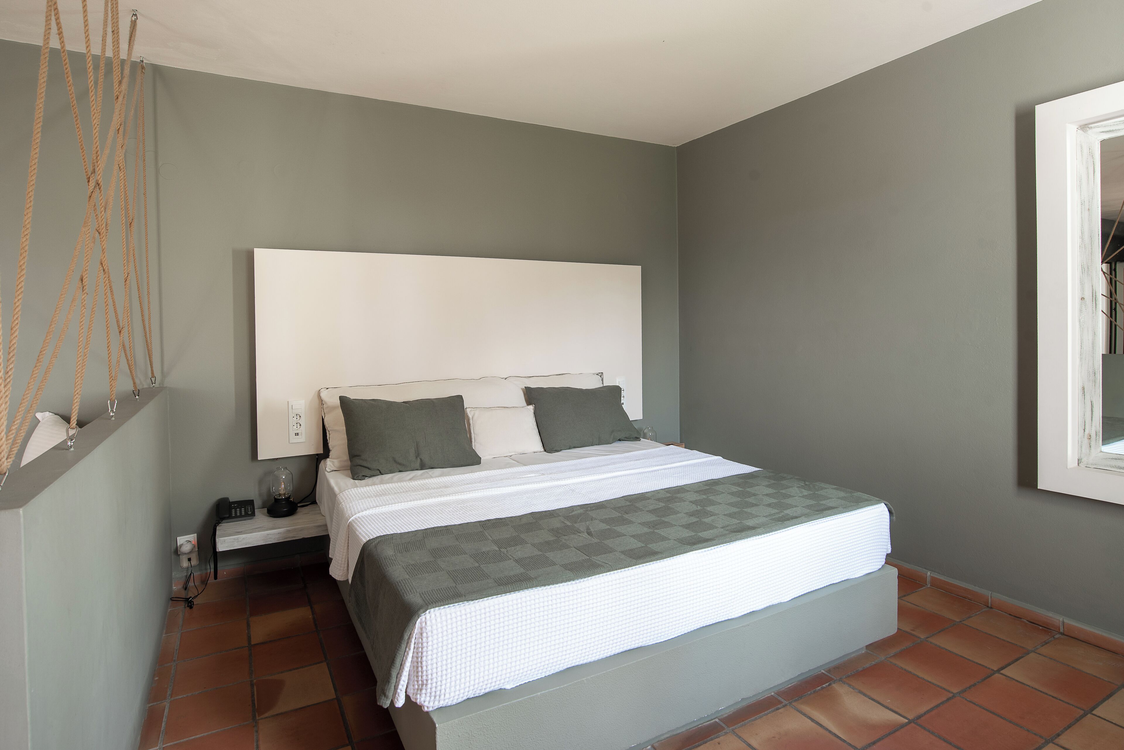 Un dormitorio con cama, mesita de noche y una lámpara fijada en la pared.