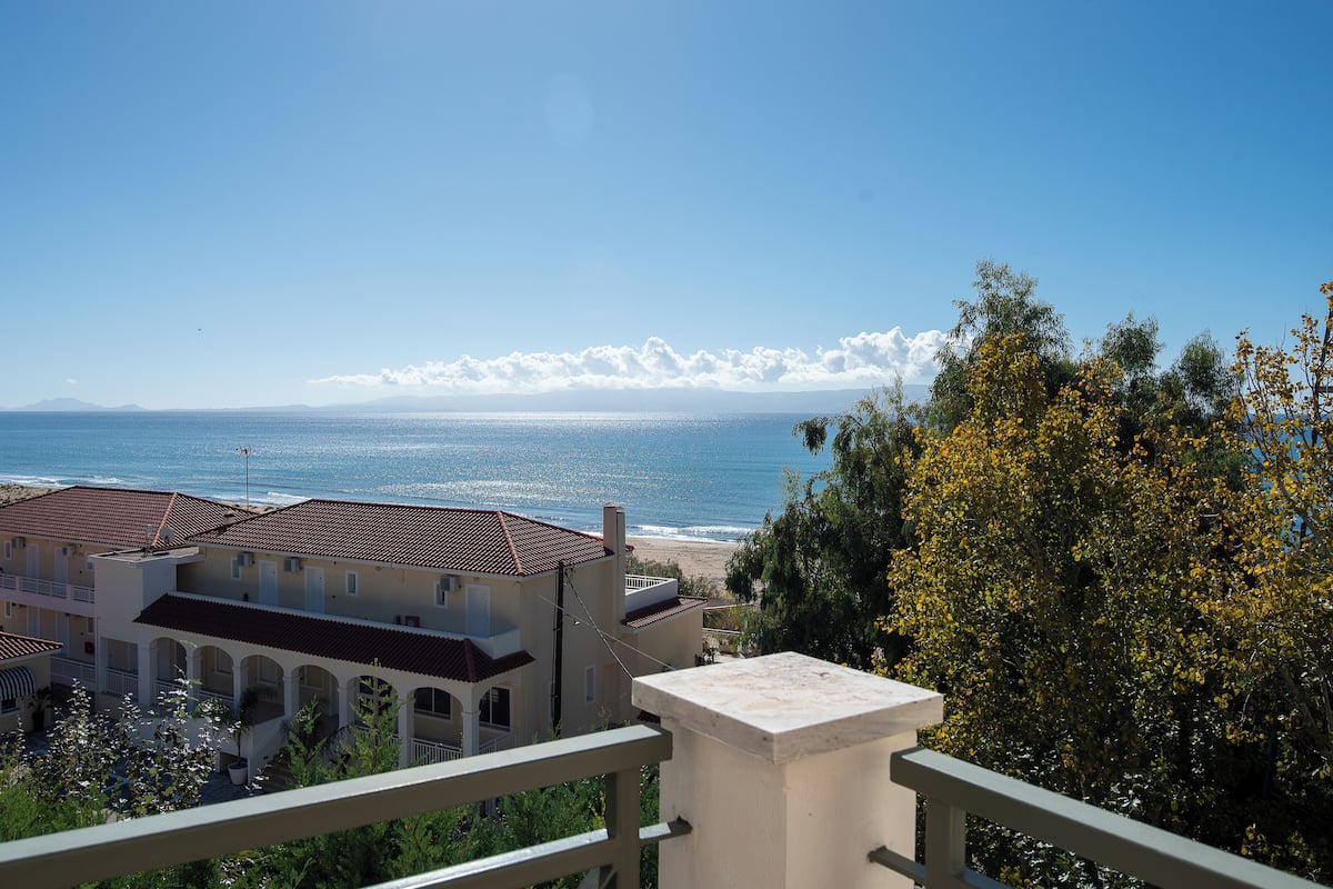A coastal hotel with a view of the sea, featuring a courtyard with arches and a balcony.