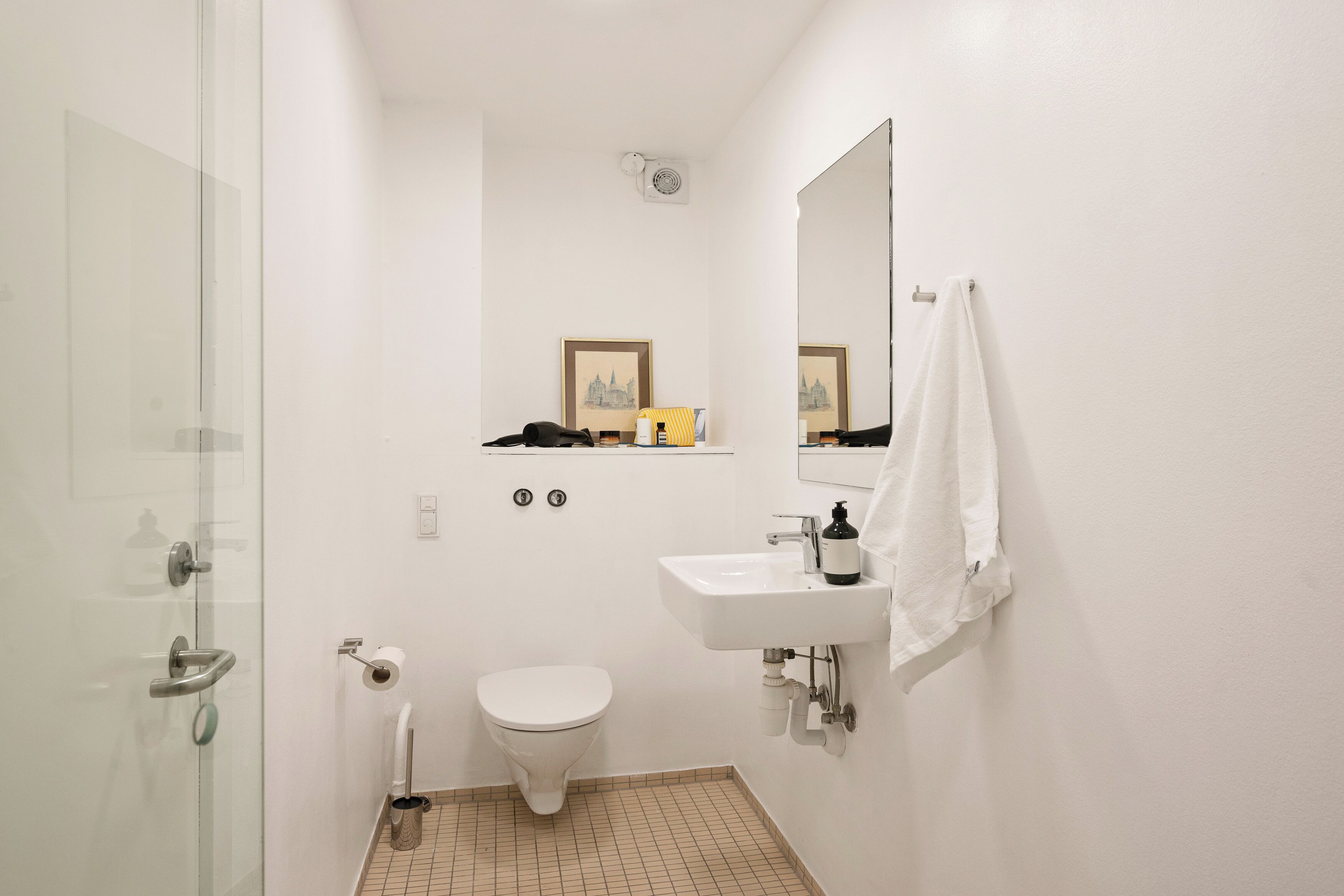 A small, clean bathroom with a toilet, sink, and glass shower door.