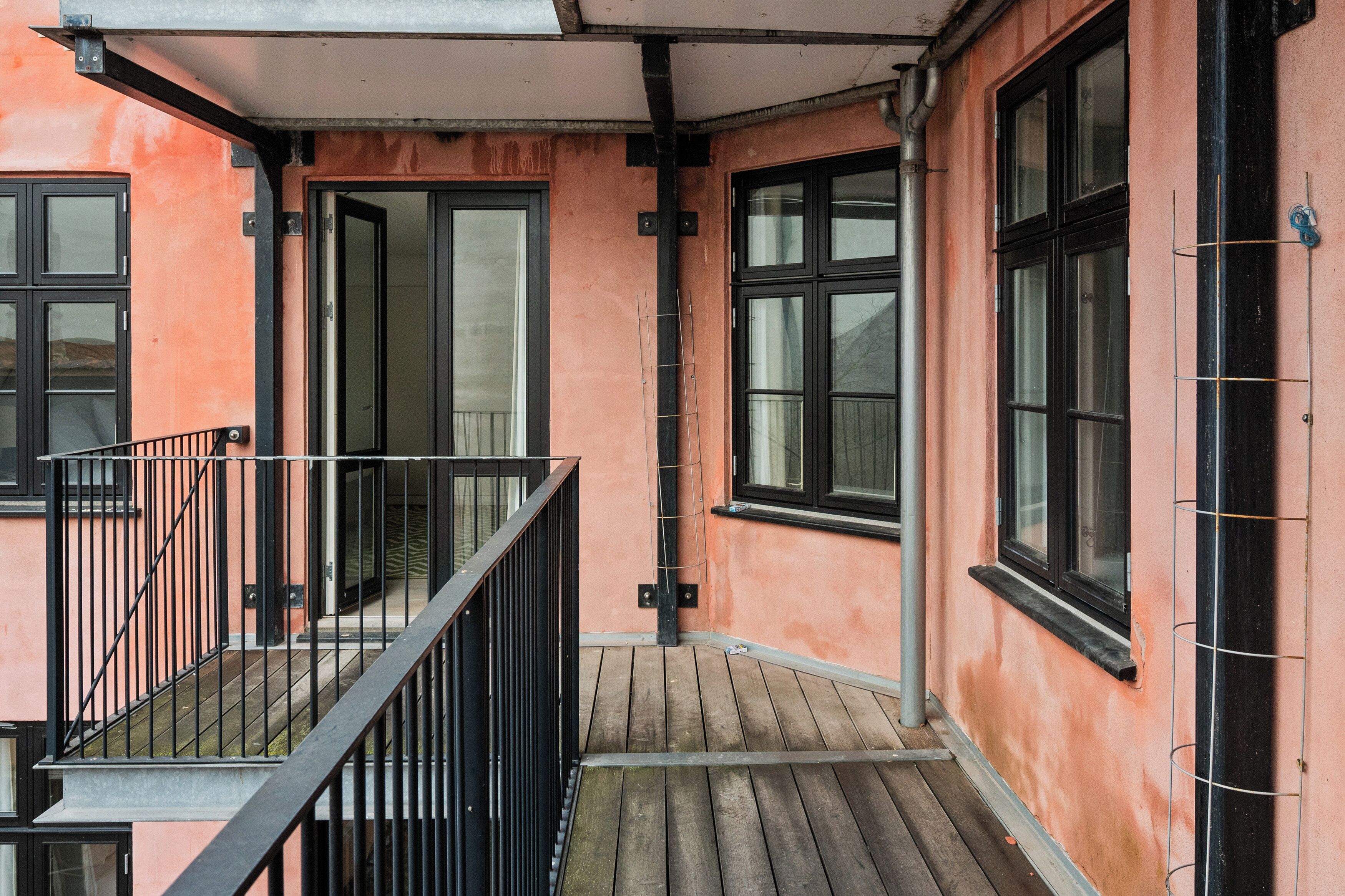 A corner of a building with a balcony, a door, and windows.