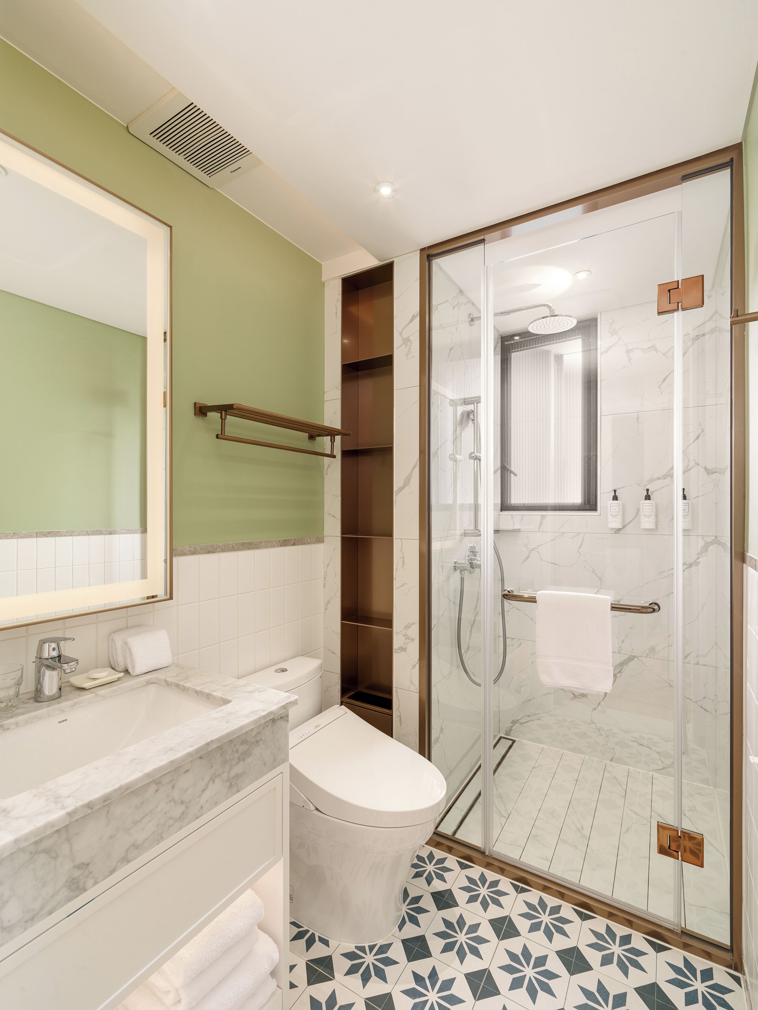 A modern bathroom with a glass shower enclosure, a marble sink, and a toilet.