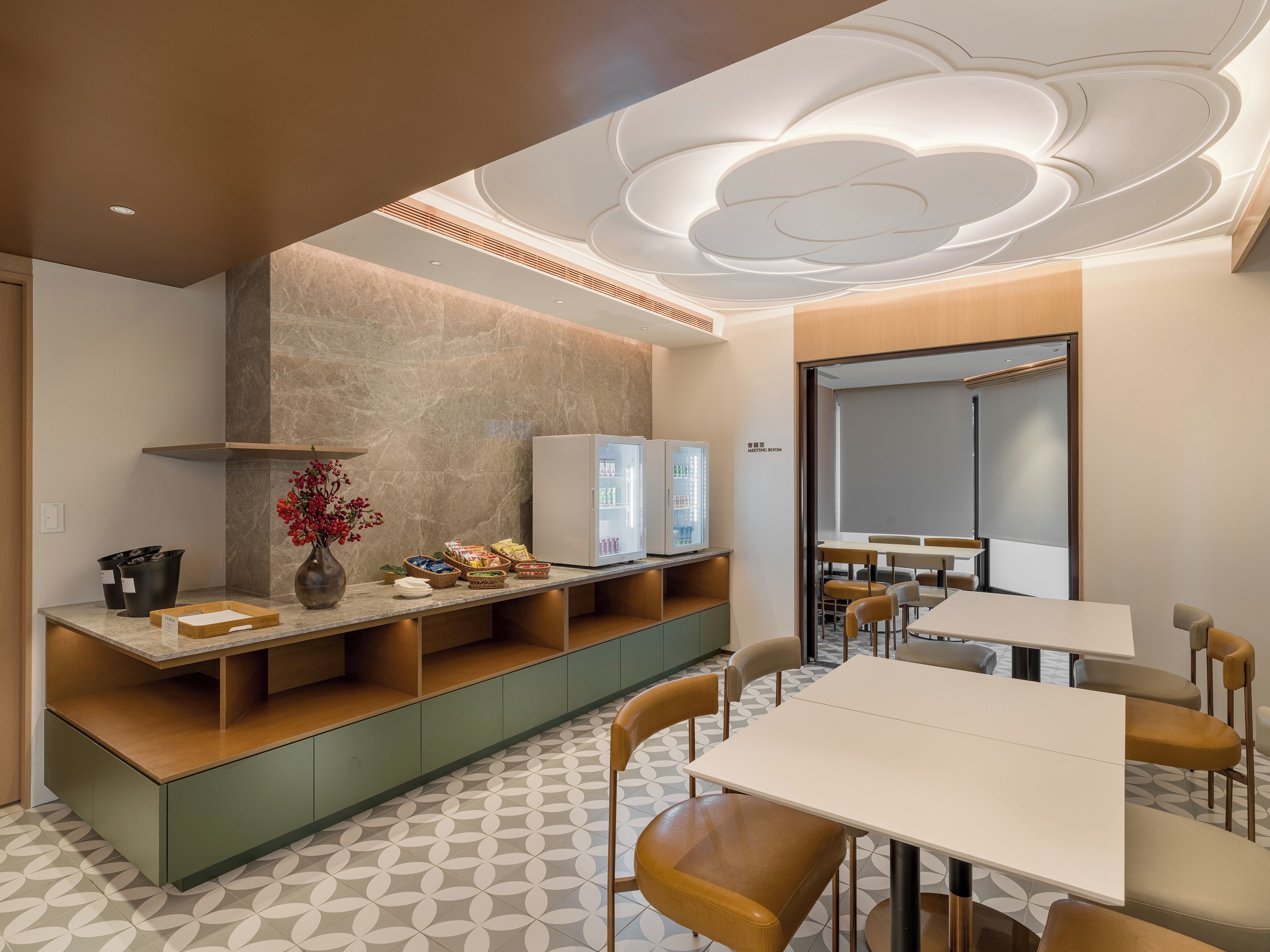 Una sala de reuniones moderna con una gran mesa, sillas, un refrigerador y una pantalla montada en la pared.