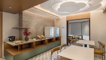 Una sala de reuniones moderna con una gran mesa, sillas, un refrigerador y una pantalla montada en la pared.