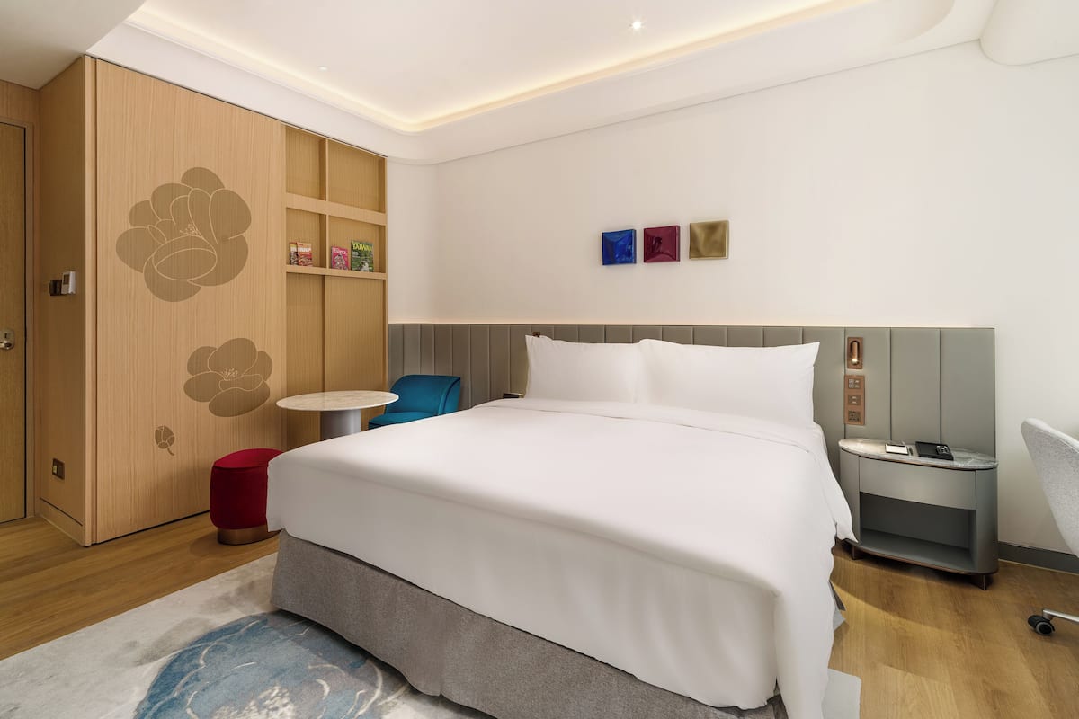 A modern hotel room with a bed, bedside table, and a small round table.