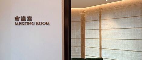 A meeting room with a table and chairs, a sign indicating the room's purpose, and a patterned floor.