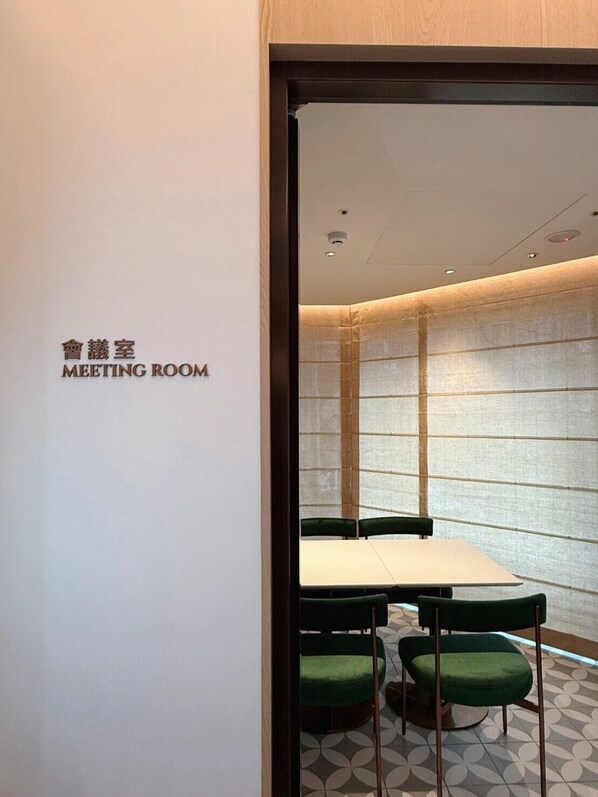 A meeting room with a table and chairs, a sign indicating the room's purpose, and a patterned floor. - EverStar Hotel (Taipei)