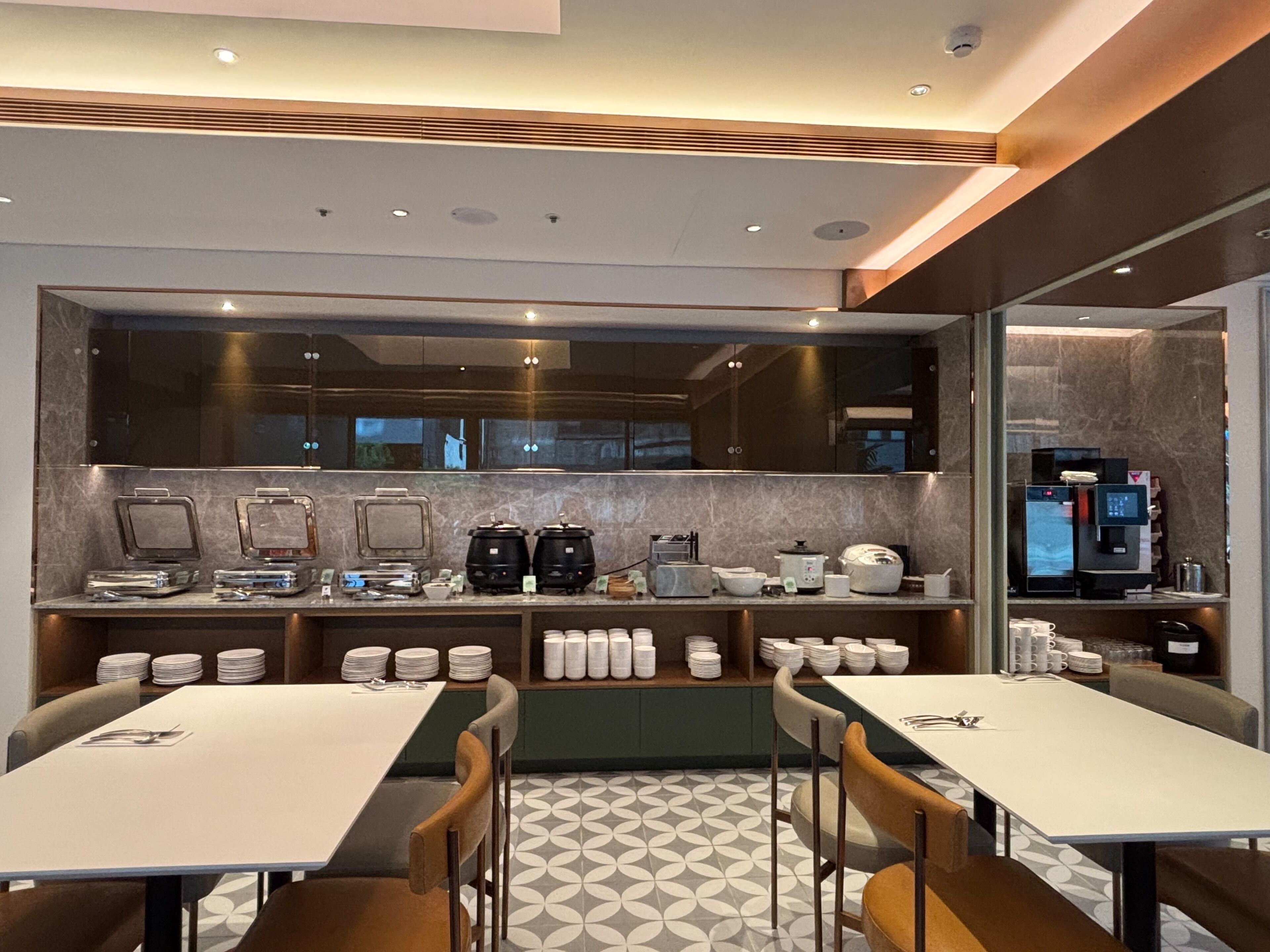 A modern kitchen with built-in appliances, a dining area with tables and chairs, and a patterned floor.