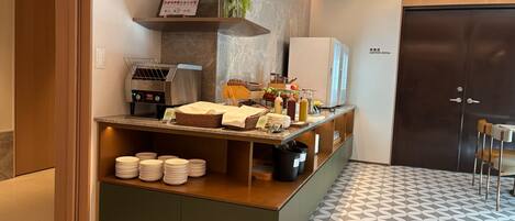 Ein Hotel-Empfangsbereich mit einer Kaffeemaschine, einem Buffet und Beschilderung für einen Konferenzraum.