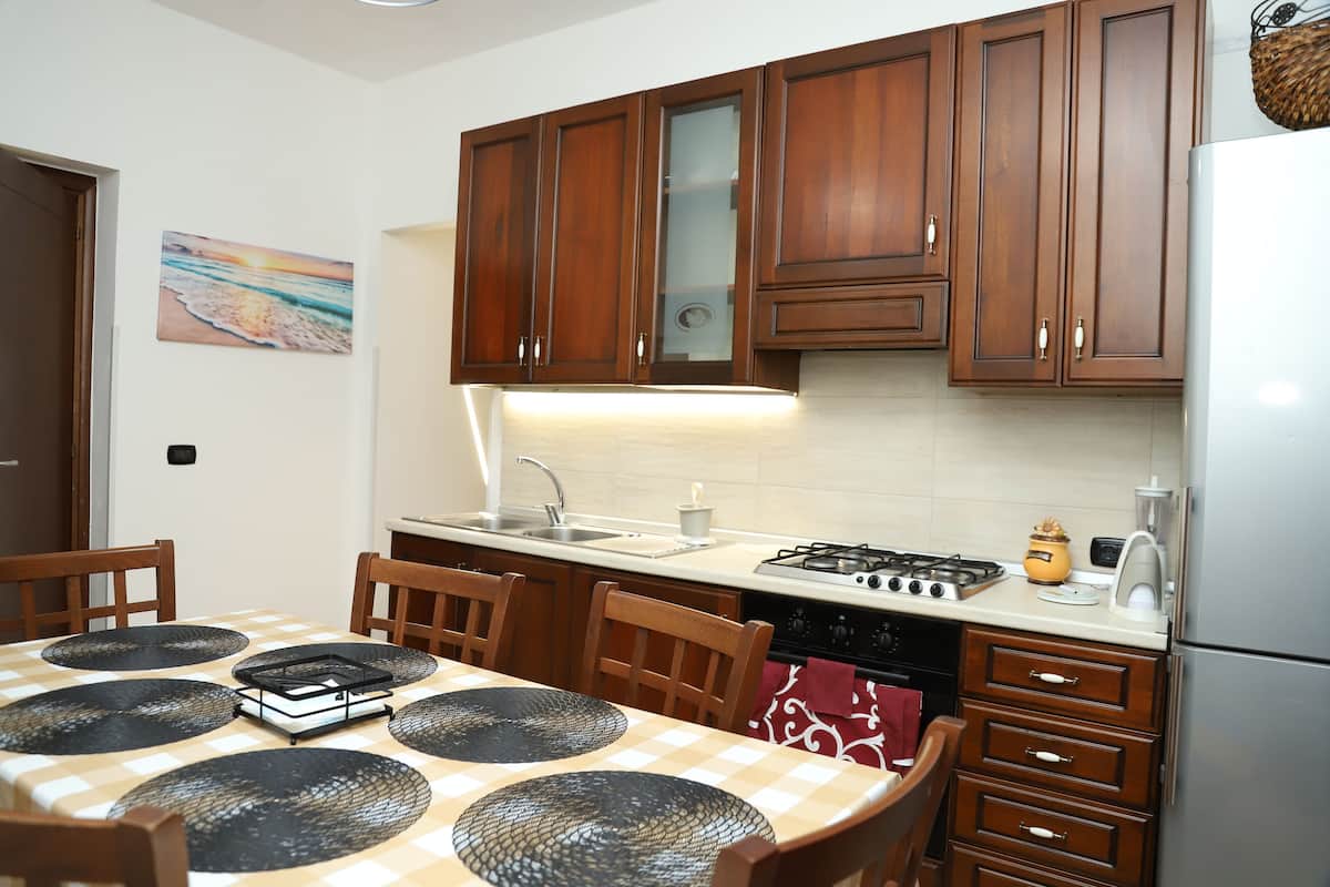 Una cocina con armarios de madera, una mesa de comedor con individuales y una estufa a gas.