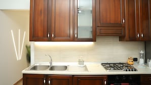 A kitchen with wooden cabinets, a stainless steel sink, a gas stove, and a countertop with a blender. - GOCCE DI LUNA (San Lucido)