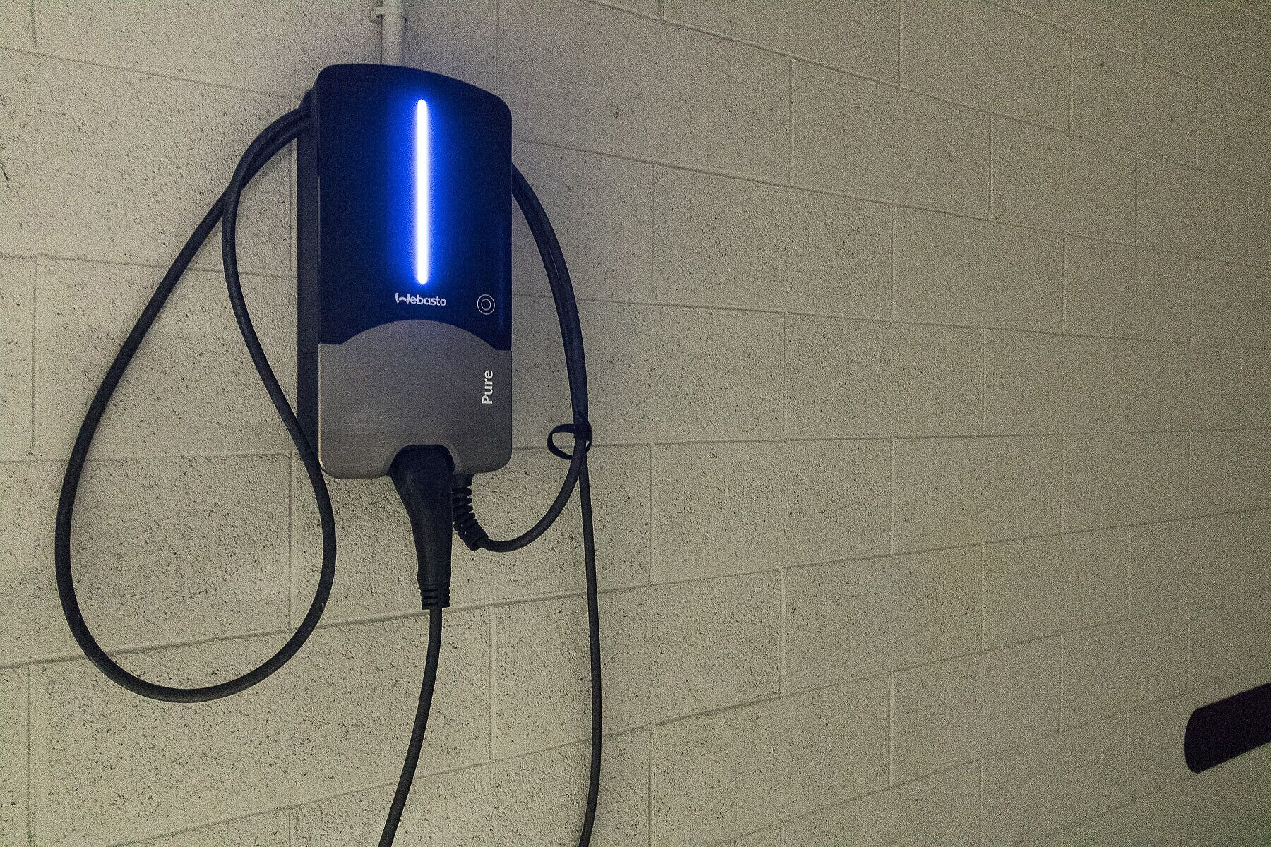 A wall-mounted device with a blue light, labeled "Webasto," connected by two cables.