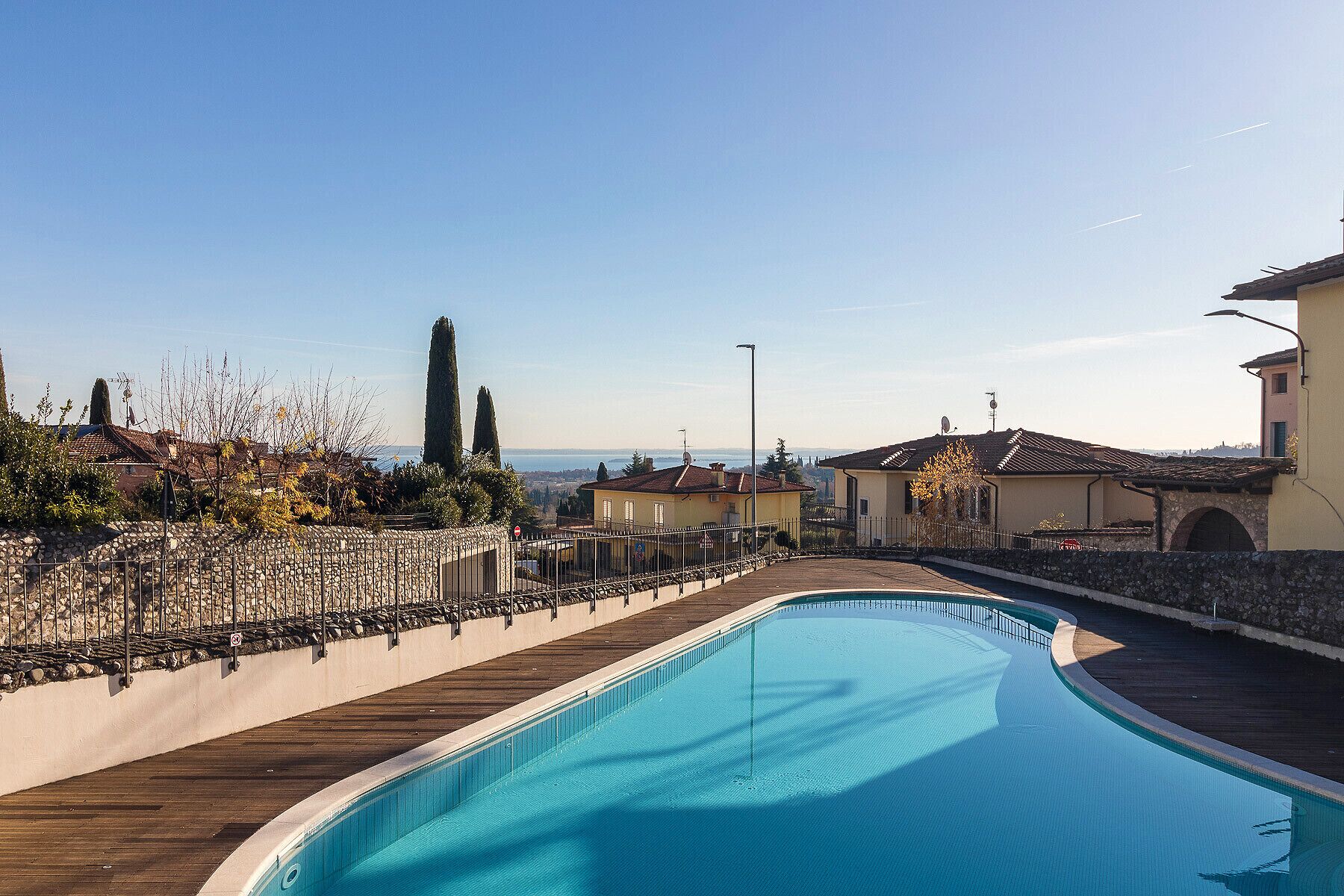 Ein Pool mit Holzterrasse, umgeben von Steinmauern und einem Steinzaun.