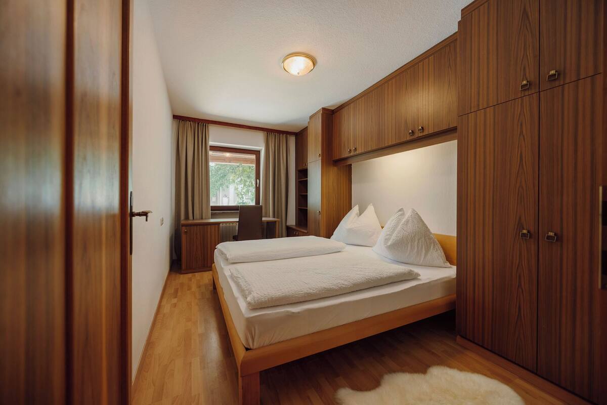 A bedroom with a wooden bed, a desk, and a wardrobe.