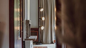 Un couloir avec un banc en pierre, une lampe sur pied et un rideau.