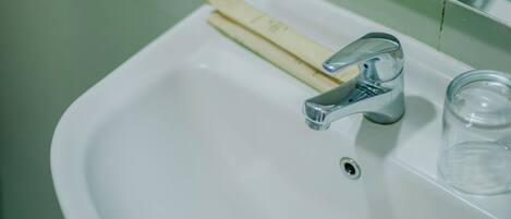 A bathroom sink with a chrome faucet, a soap bar, and a glass.