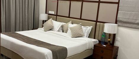 Un dormitorio de hotel con una cama grande, mesitas de noche y un cabecero con el logotipo del hotel.
