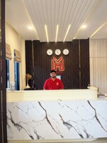Un mostrador de recepción de hotel con encimera de mármol, un reloj y un logotipo en la pared.