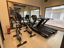 Un gimnasio con cintas de correr, elíptica y bicicleta estática.