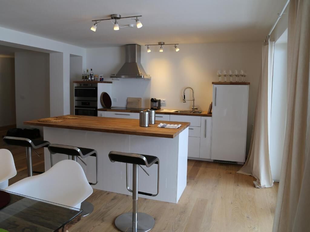 Una cocina moderna con una isla central, taburetes de bar y un comedor.