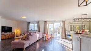 Un salon moderne comprenant un canapé, un téléviseur et un coin repas avec une table et des chaises.