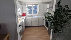 Une cuisine de taille réduite avec des meubles blancs, une fenêtre et un évier.