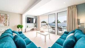 A modern living room with a large sofa set, a flat-screen TV, and a dining area with a view of the outdoors. - Vacation Villa 'Villa Esmerad' with Mountain Views, Wi-Fi and Air Conditioning (Playa Blanca)