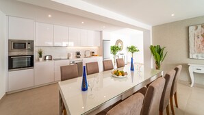 A modern kitchen with white cabinets, a built-in oven, and a dining area with a glass table and chairs. - Vacation Villa 'Villa Esmerad' with Mountain Views, Wi-Fi and Air Conditioning (Playa Blanca)