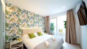 A hotel room with a bed, a nightstand, a potted plant, and a view of the outdoors. - Vacation Villa 'Villa Esmerad' with Mountain Views, Wi-Fi and Air Conditioning (Playa Blanca)