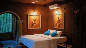 Ein Schlafzimmer mit einem großen Bett, zwei Wandleuchten, einem Fenster mit Gitterstäben und einer Ziegelwand.