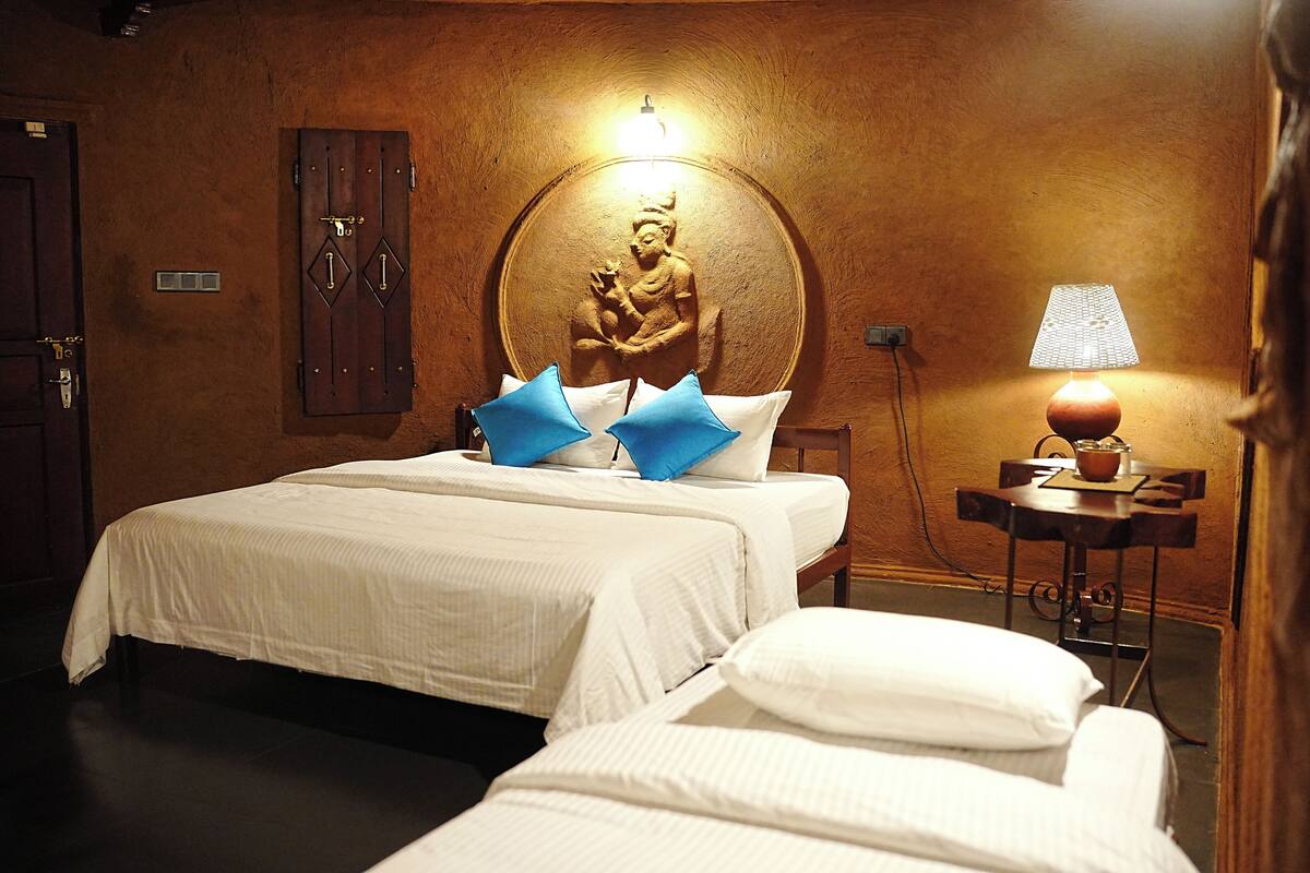Een hotelkamer met twee bedden, een wandsculptuur, een lamp en een klein tafeltje.