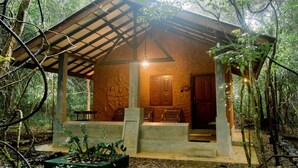 Eine rustikale Holzhütte mit steinernen Fundamenten, einer Veranda mit Bänken und einer Tür.