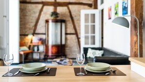 A dining table with two sets of plates and wine glasses, a lamp, and a rustic brick wall in the background. - Elegant and bright apartment in the center (Granada)
