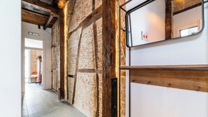 A hallway with exposed brick walls, wooden beams, and a white door with a metal handle. - Elegant and bright apartment in the center (Granada)